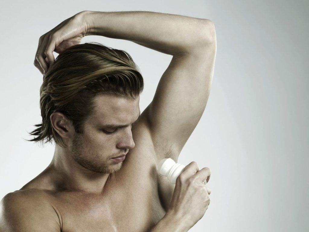 0. Hombre usando desodorante en axila, cuidado personal, higiene masculina, estilo de vida saludable.