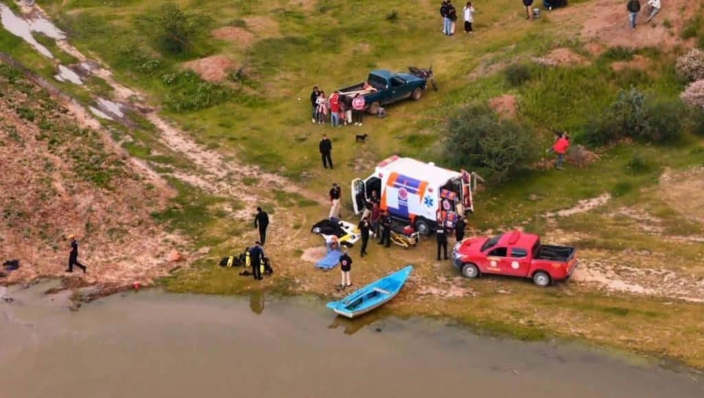 Accidente de embarcación en río con ambulancia y equipo de rescate en la escena.