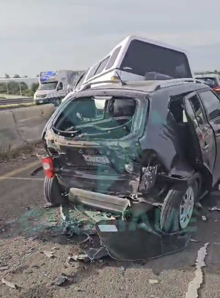 Caída de vehículo en accidente automovilístico en carretera, daños severos en parte trasera y lateral.