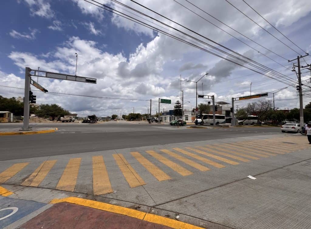 Vehículos en cruce peatonal con semáforo en ciudad, cielo nublado, infraestructura moderna, movilidad urbana en México.