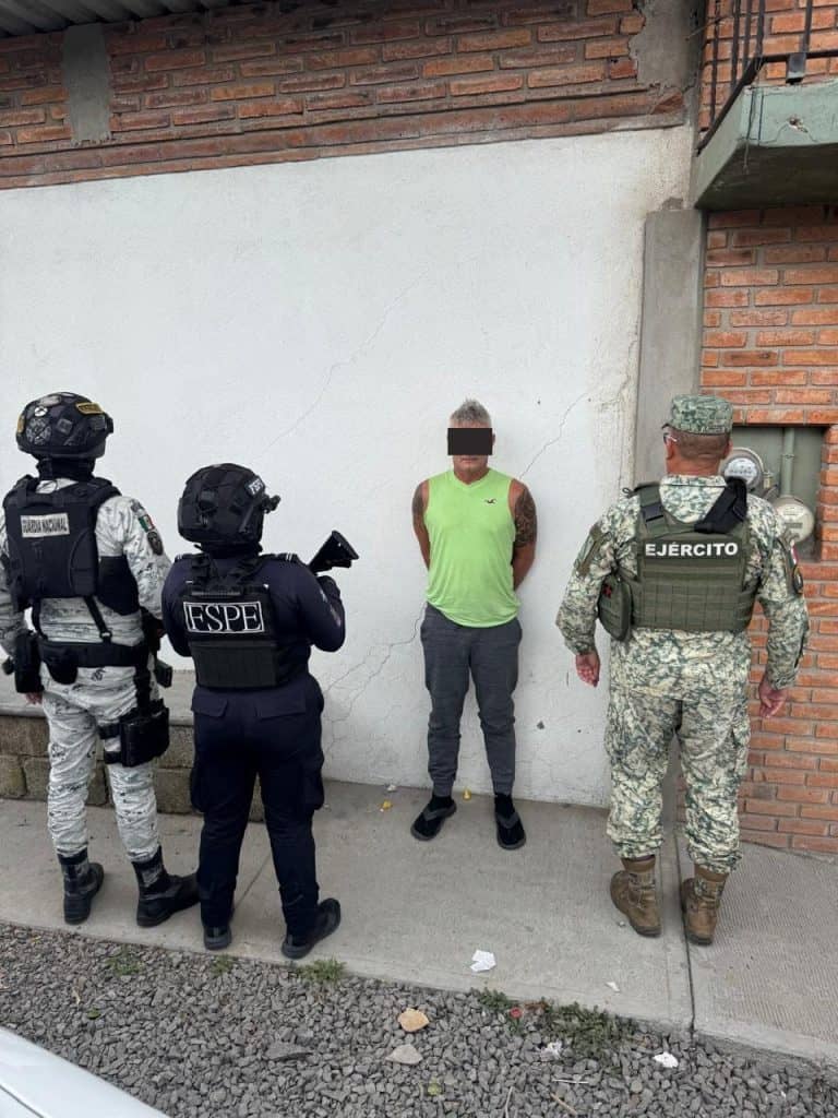 Hombre detenido por las fuerzas armadas, con armas y uniformes del ejército y fiscal en una zona urbana.