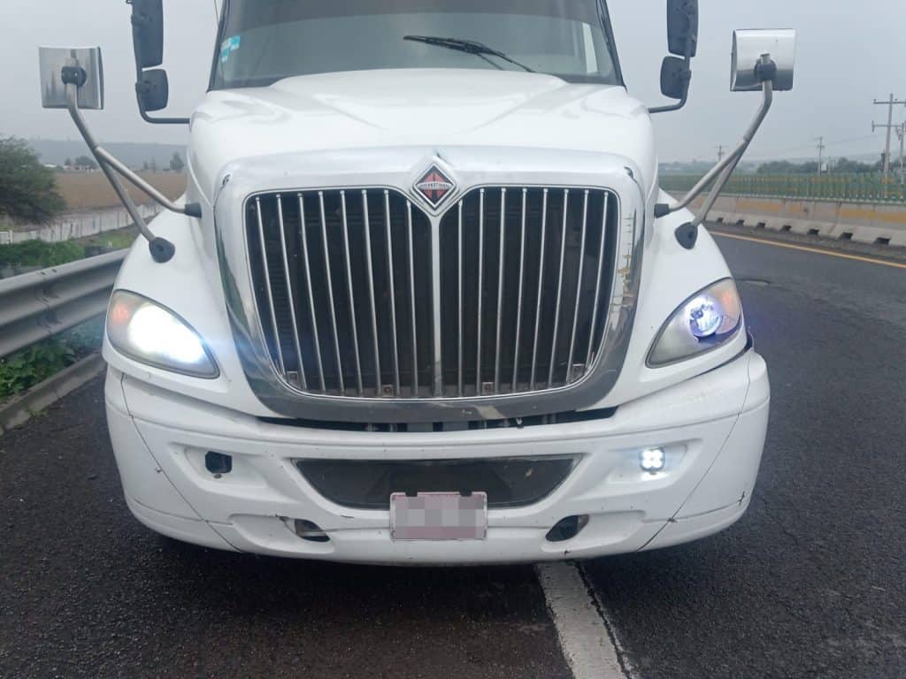 Recuperan tractocamión con sandalias valuadas en 117 mil pesos Camión blanco en carretera con neumático pinchado y luces encendidas, atendiendo una emergencia vial en México.