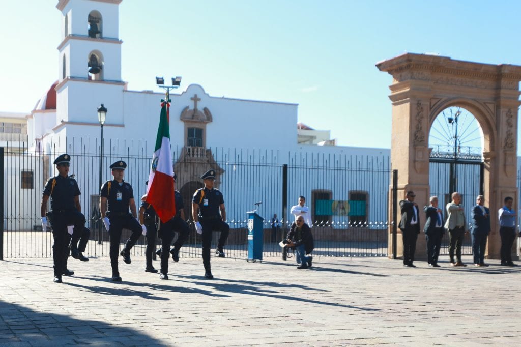 1. Policía en ceremonia en Cuéntame Iglesia en México, desfile cívico y bandera mexicana en evento oficial.