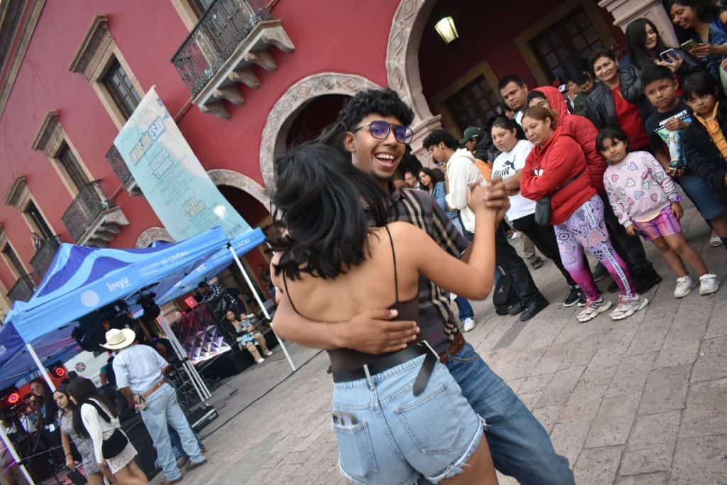 Diversión en pareja bailando en evento cultural en México, expresión de alegría y música en la calle.