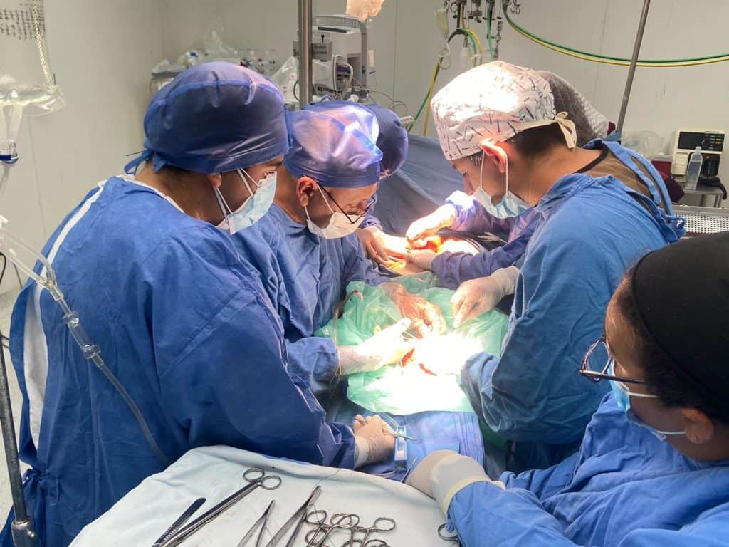 Cirujanos realizando operación en hospital, equipo médico en acción, atención quirúrgica, salud y medicina avanzada.