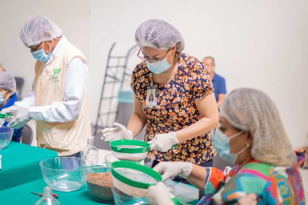 Alto text only: Personal de salud preparando alimentos en un taller de cocina saludable con mascarillas.