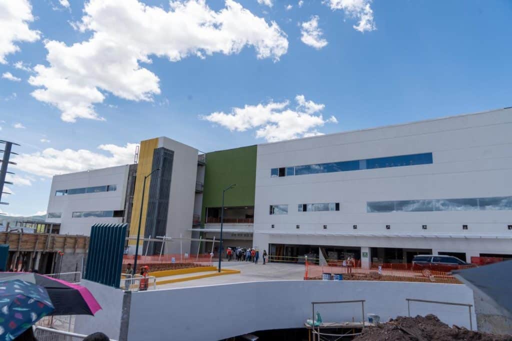 Moderno edificio en construcción con fachada blanca y detalles en verde y amarillo.