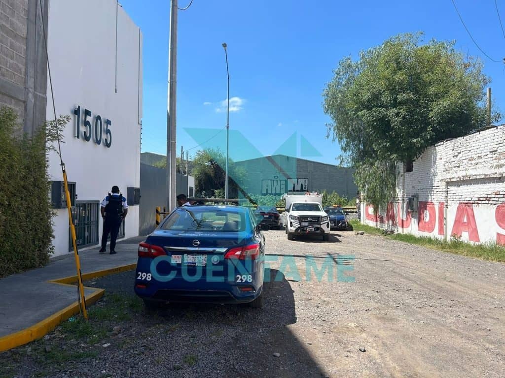 1. Policía y carros de policía en escena en zona urbana con edificio y muro pintado en letras rojas.