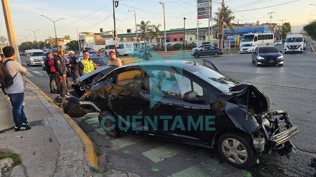 Accidente de coche en la vía pública con varias personas y servicios de emergencia presentes.