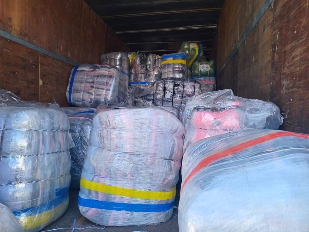 Recupera Secretaria de Seguridad de Guanajuato carga de ropa con valor superior al millón de pesos Alto texto: Paquetes de ropa y textiles almacenados en una caja de mudanza cerrada.