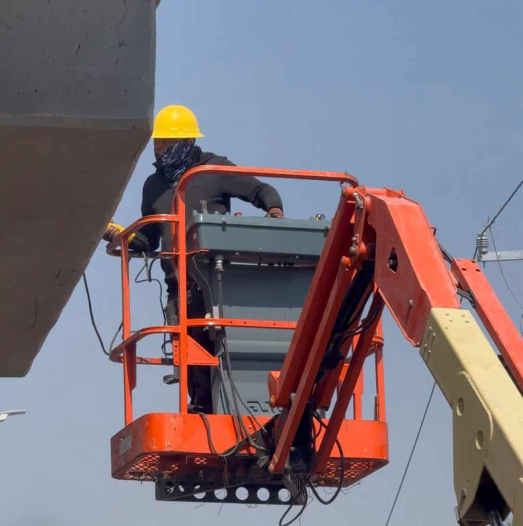 Trabajador en elevador de construcción, mantenimiento en altura, herramienta en trabajo en alturas.