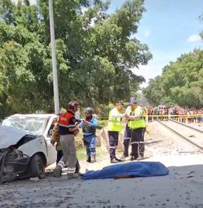 Accidente de tránsito con cuerpo en la carretera, presencia de policías y emergencias, imagen impactante.