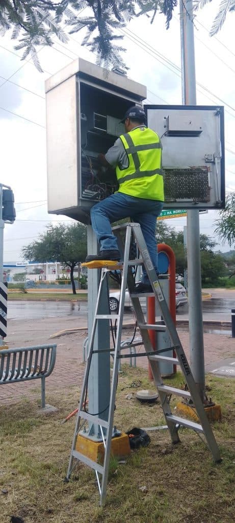 1. Técnico reparando infraestructura eléctrica en poste de luz exterior.