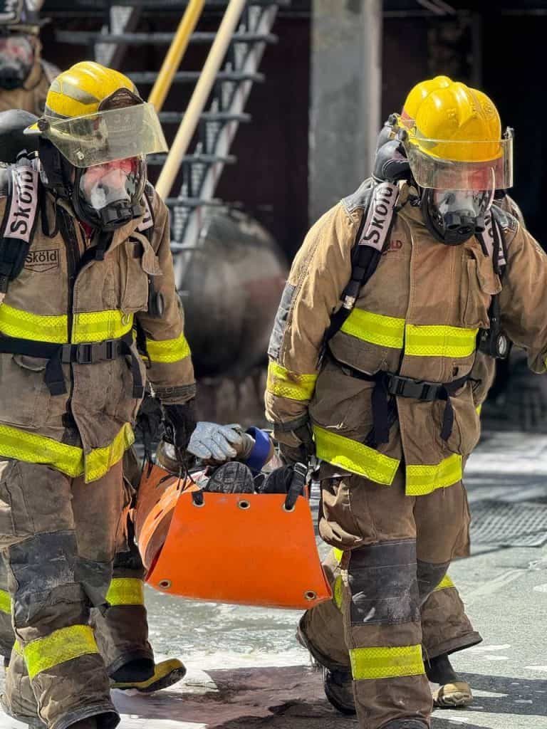 Bomberos en acción usando equipo de protección en un incendio.