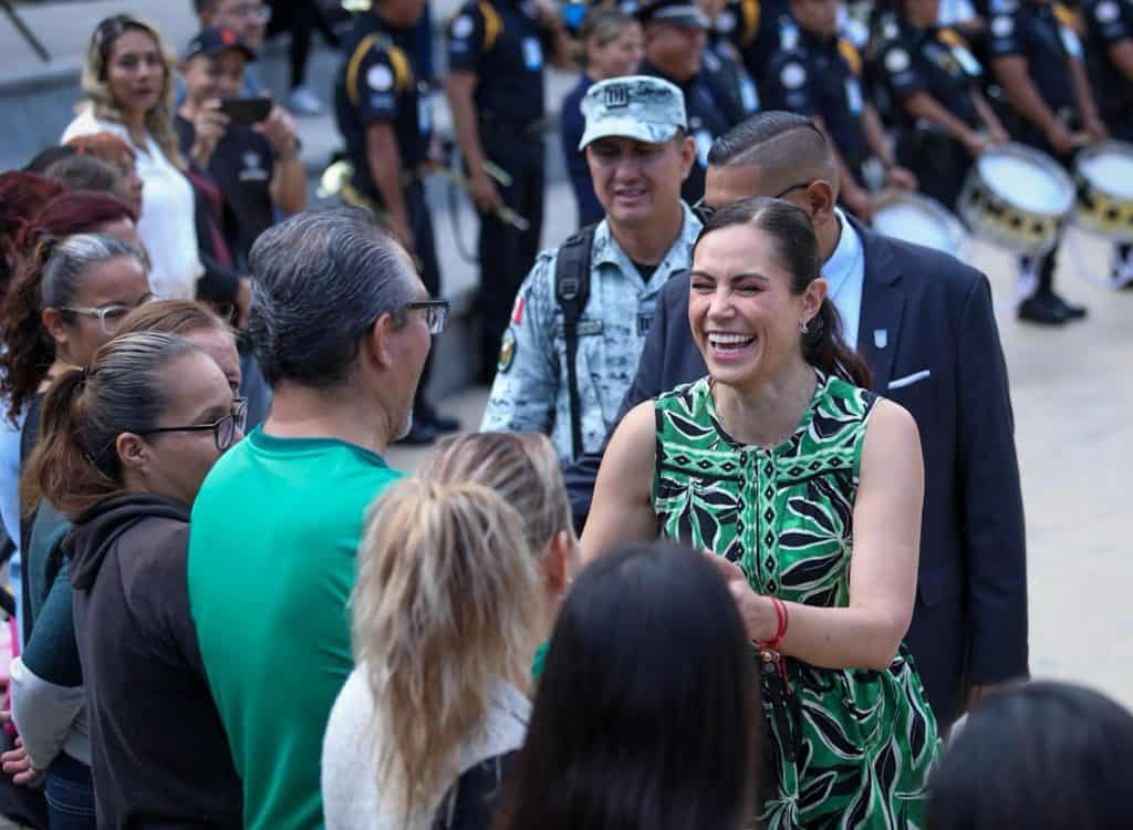 Sonriente mujer saludando a grupo de personas en evento público de Cuentame.