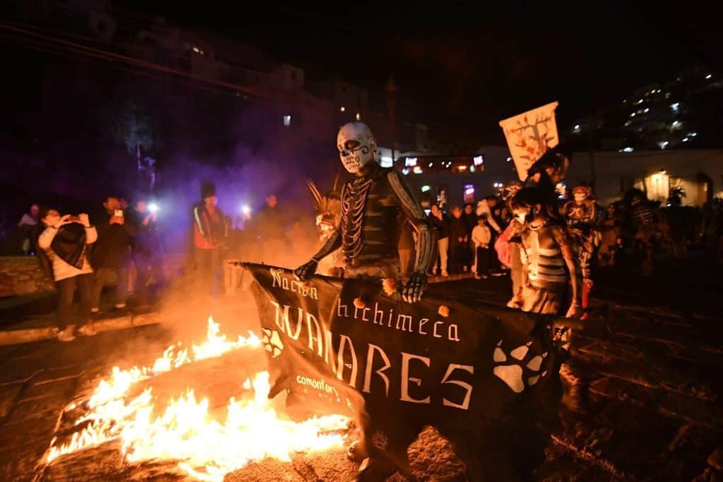 Personas en celebración del Día de Muertos con calaveras y ofrendas en un evento tradicional mexicano.
