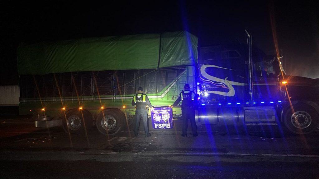 Choque entre camión y auto en la carretera, agentes de la policía realizan inspección nocturna.