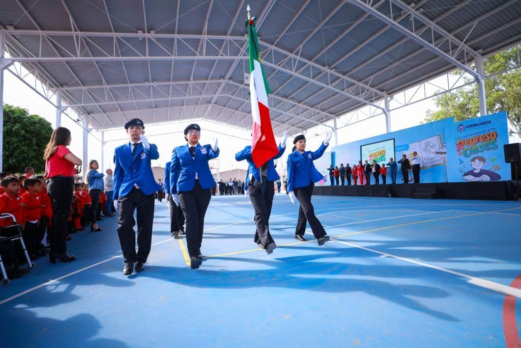 Estudiantes en ceremonia cívica con bandera de México en una escuela de Guanajuato.