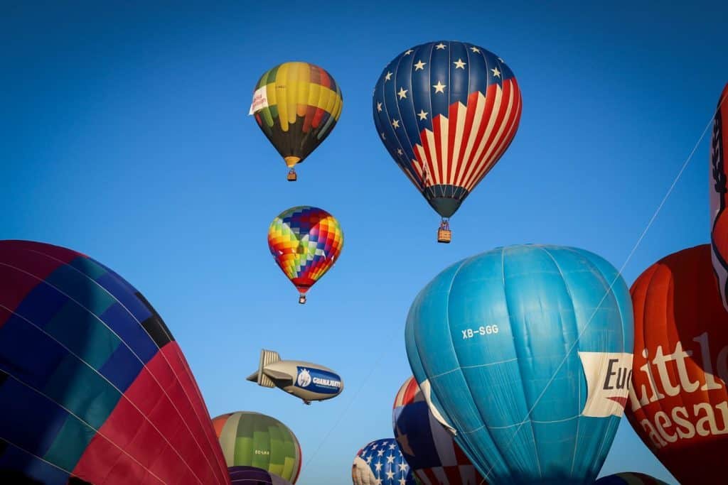 Coloridos globos aerostáticos en cielo azul, espectáculo visual y aventura en vuelo libre.