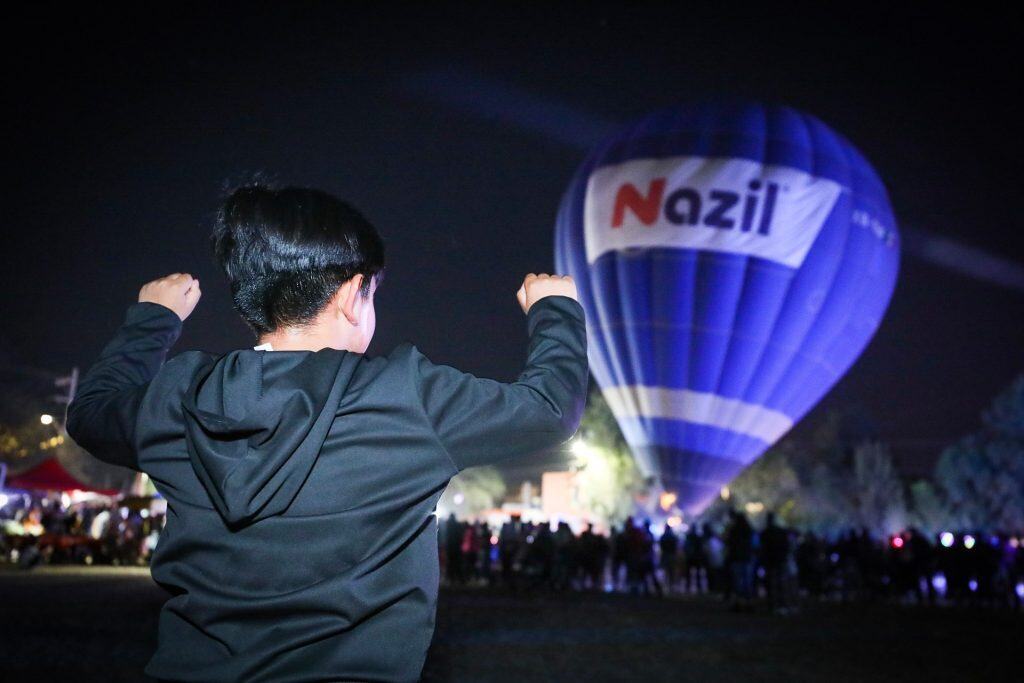 Viven un opening histórico: 17 mil personas disfrutan el encendido de globos Colorido globo aerostático con la palabra "Nazil" en un evento nocturno en México.