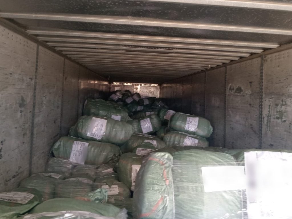 Bultos y paquetes en el interior de un remolque de carga con paredes de madera.