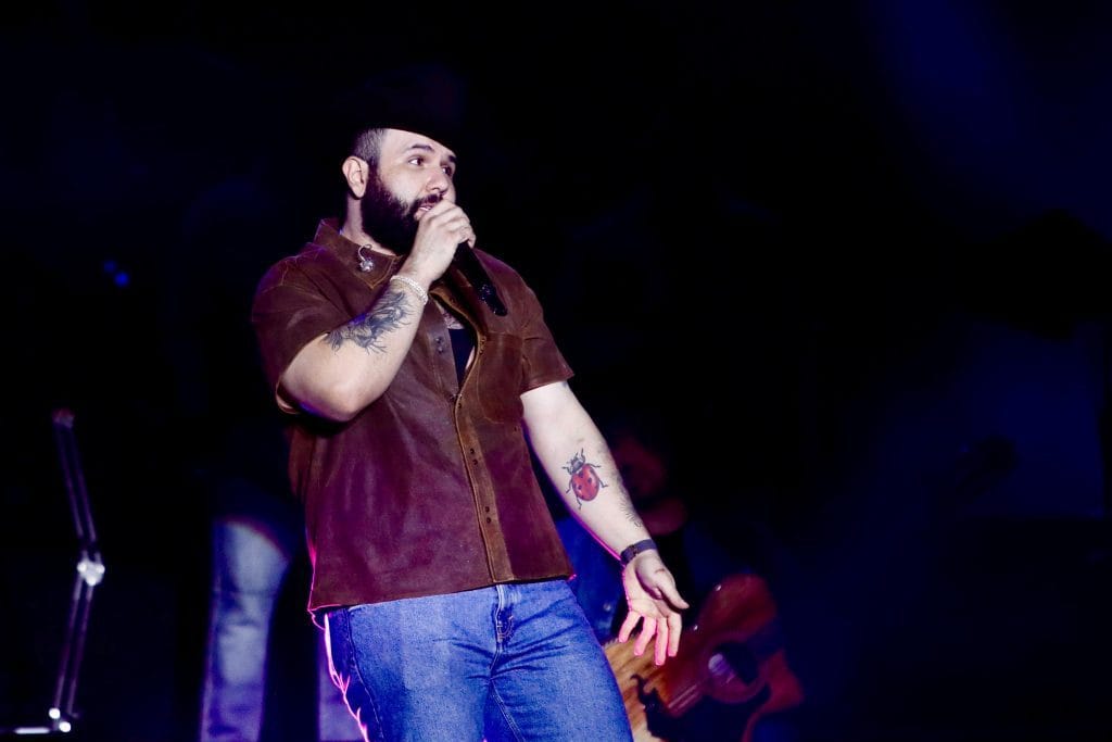 Rapero con tatuajes en el escenario durante show musical en vivo.