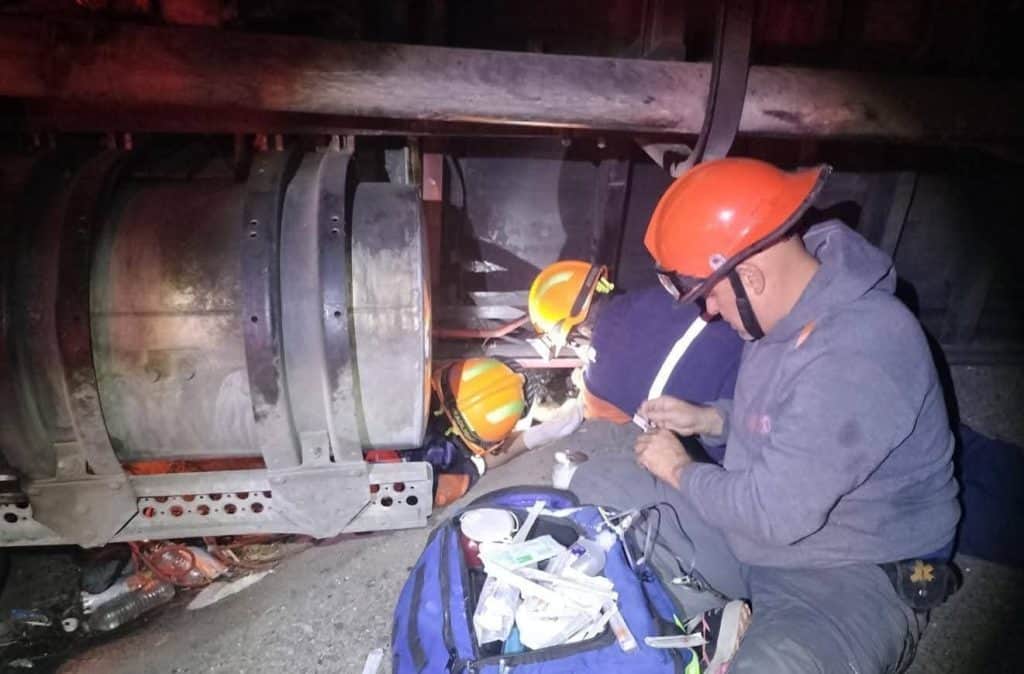 1. Técnicos en mantenimiento de vehículos de accidente laboral con casco de seguridad naranja.