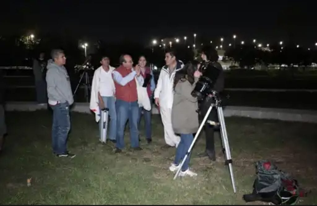 Personas en grabación nocturna para programa de televisión en un parque.