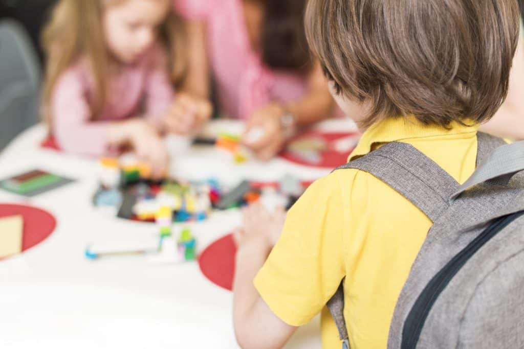 Diversión infantil y aprendizaje en juegos con niños en una mesa escolar.