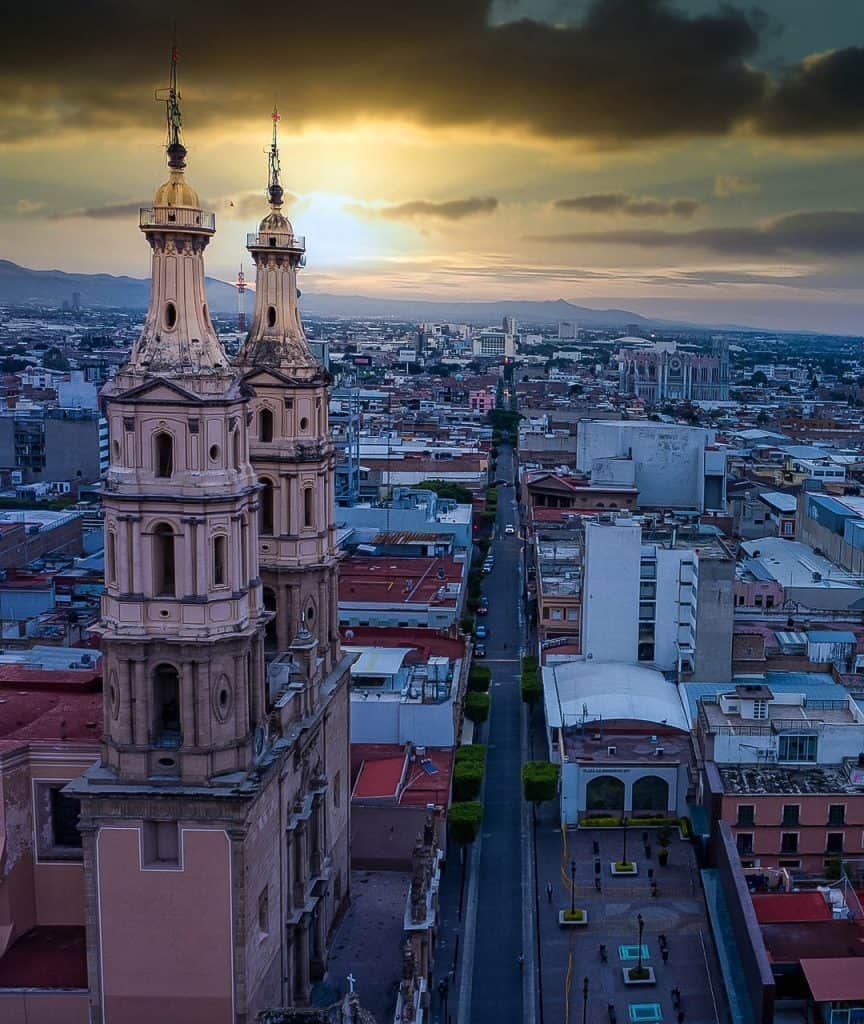1. Iglesia histórica en la ciudad al atardecer con cielo nublado y horizonte urbano vibrante.
