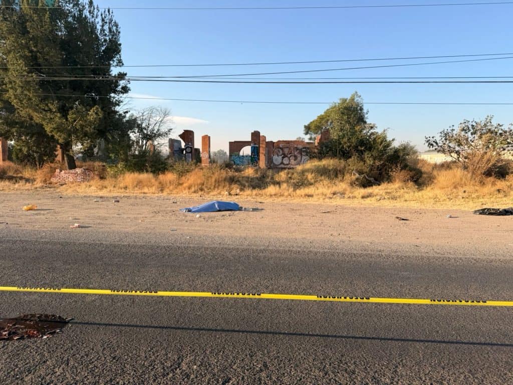Cadáver cubierto con tela en la calle, escena de un posible incidente o crimen, en un ambiente urbano y descuidado.