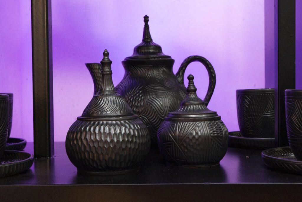 Vajilla africana de cerámica negra con patrones geométricos y textura única en exhibición temática African Dream.