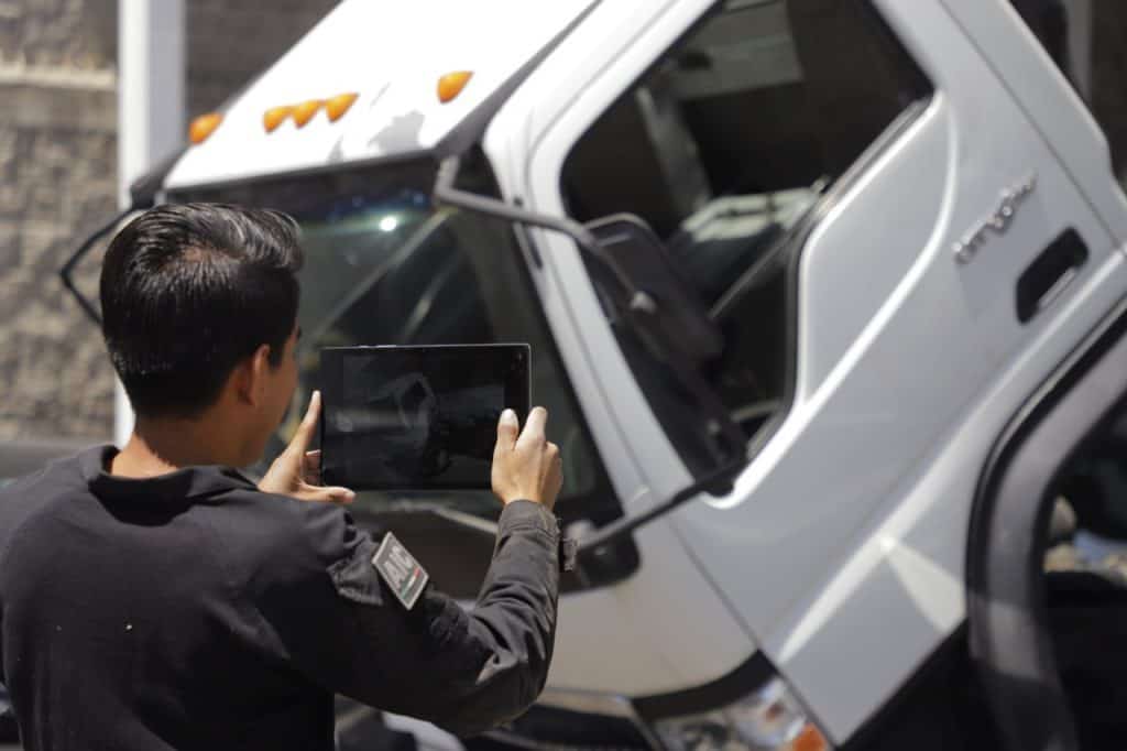 1. Persona tomando foto de vehículo siniestrado con tableta en la calle.