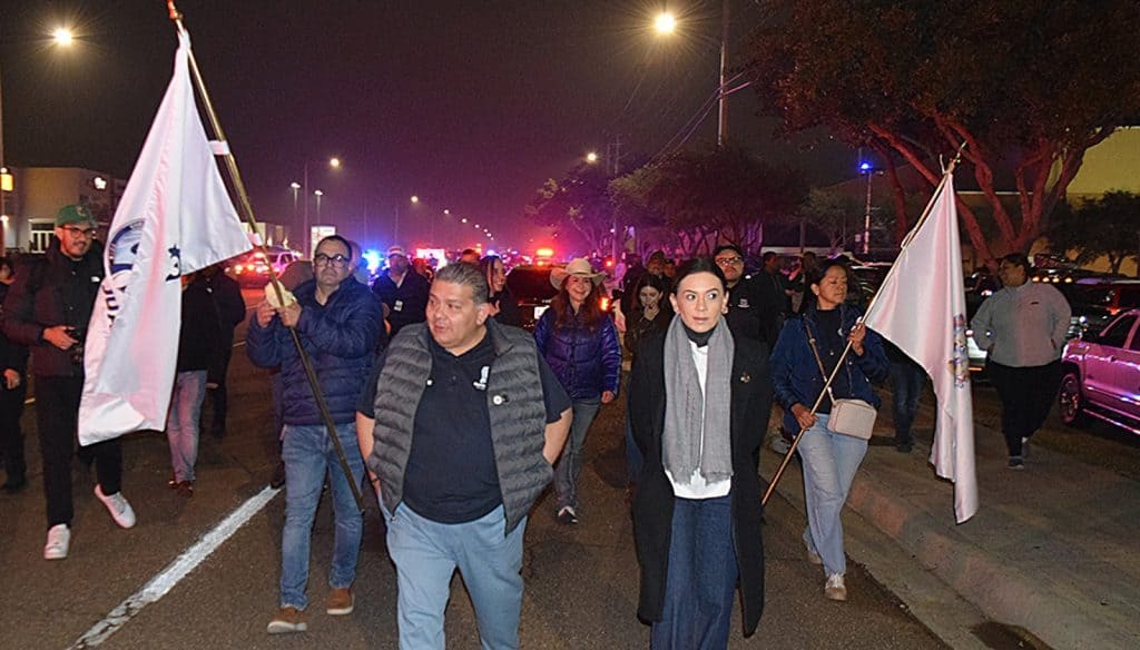 1. Personas participando en marcha pacífica con banderas en la noche, seguridad y comunidad en evento social.