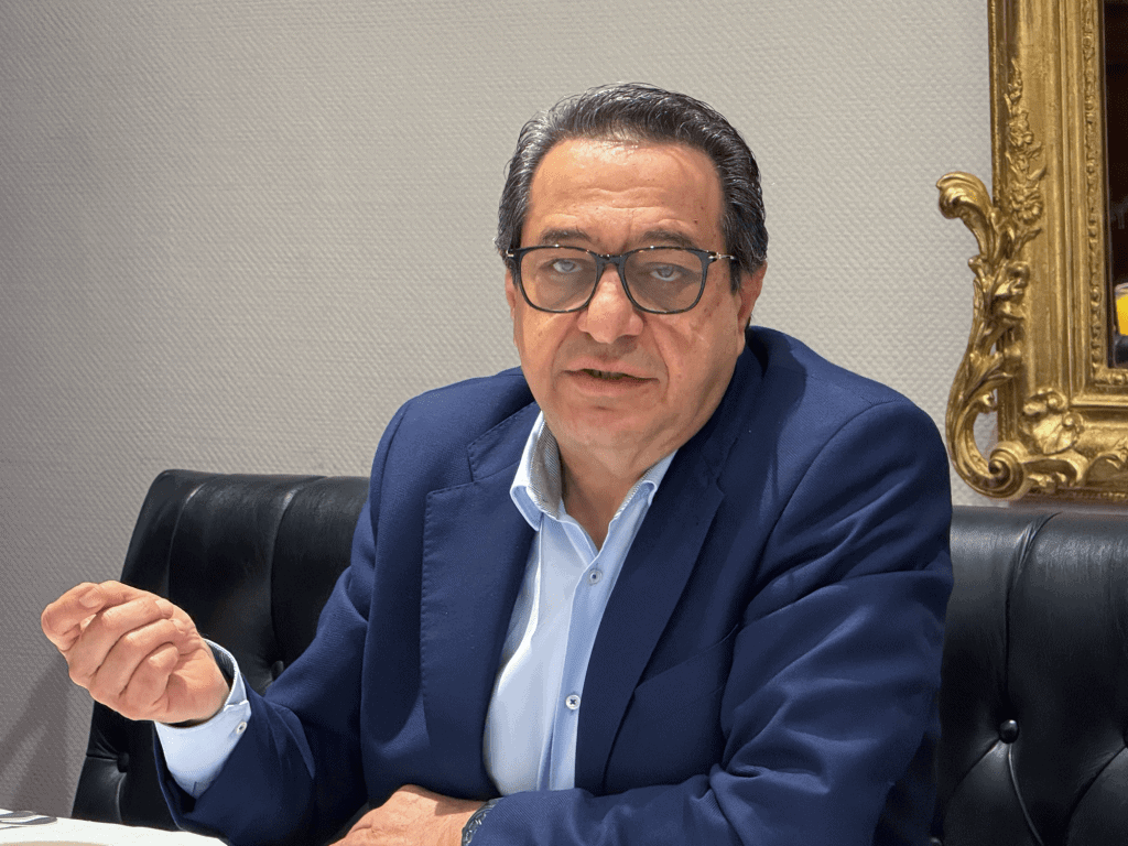 Profesional hombre de negocios en traje azul y gafas en entorno formal con decoración elegante.