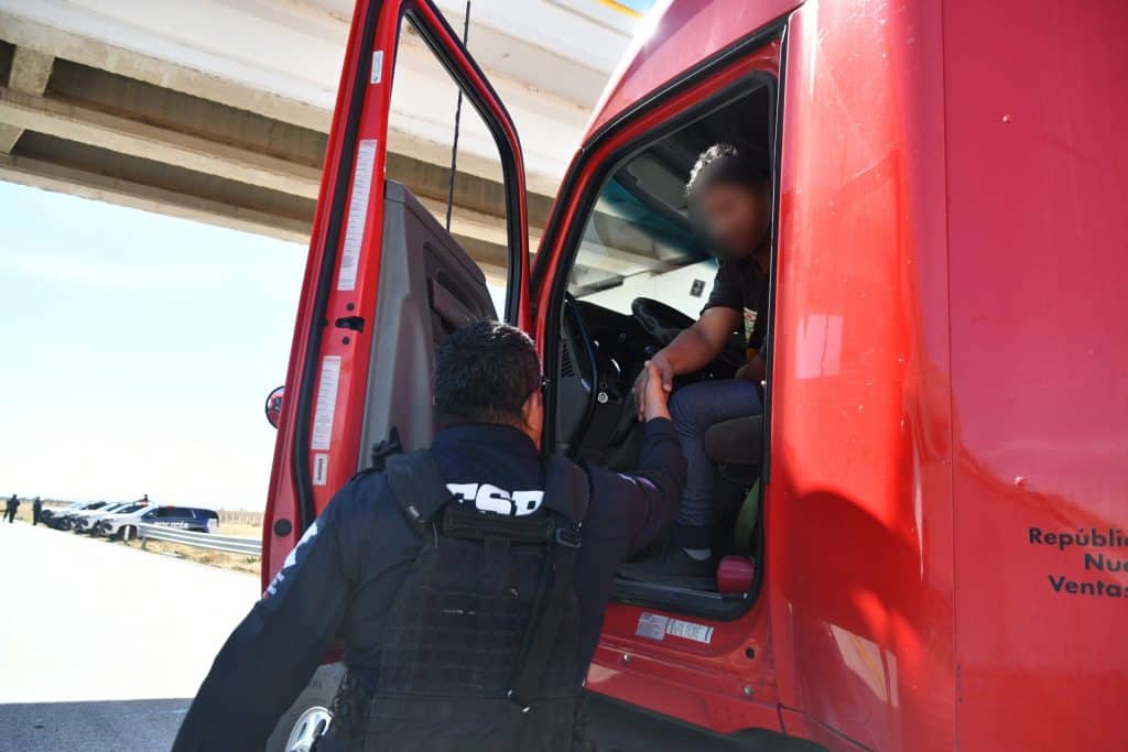 Policía atendiendo a conductor en carretera, control de tránsito, seguridad vial y emergencia.
