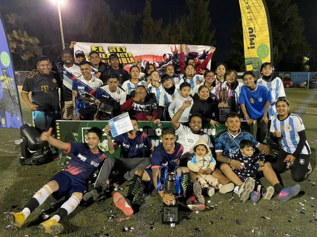 Jóvenes en rehabilitación brillan en la final del Torneo León 450 Campeonas de fútbol celebrando victoria con sus equipos en un campo nocturno, con trofeos y sonrisas tras el partido.