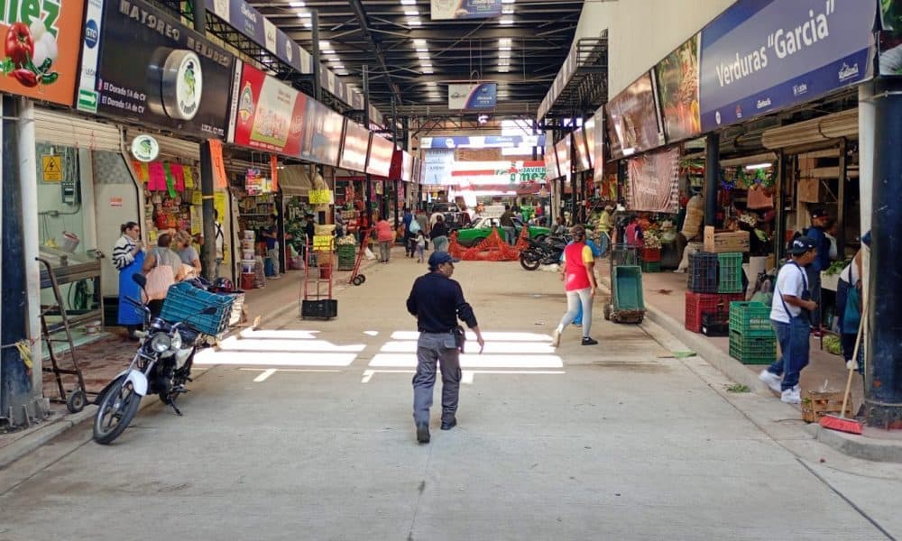 Concluye la primera fase de la rehabilitación del Descargue Estrella Camión de mercado local en un pasillo cubierto lleno de personas y puestos de verduras y frutas.