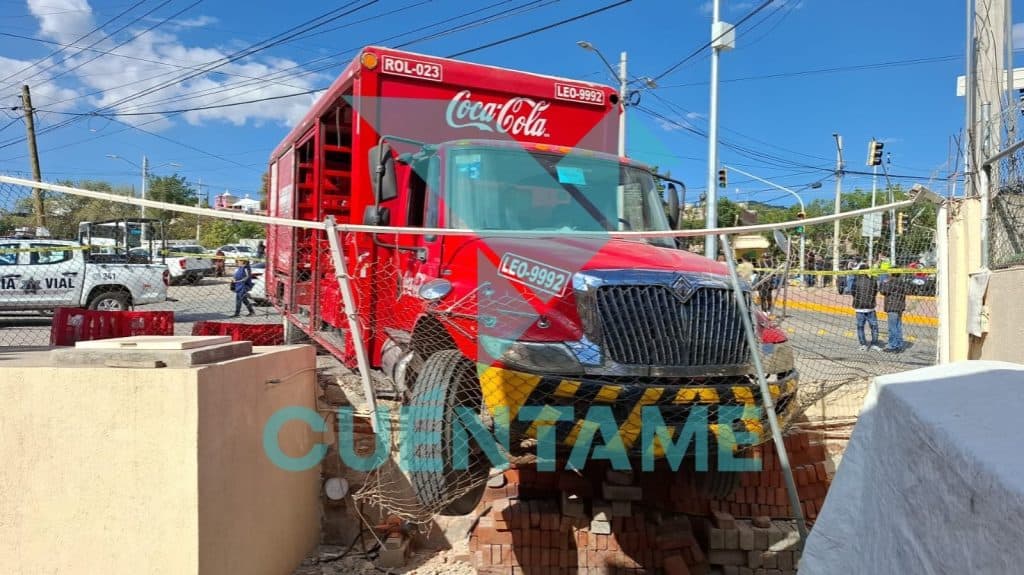 Camión de Coca-Cola en accidente con barricada y daños en la zona urbana.