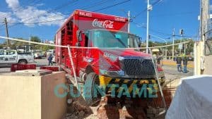 Camión de Coca-Cola en accidente con barricada y daños en la zona urbana.