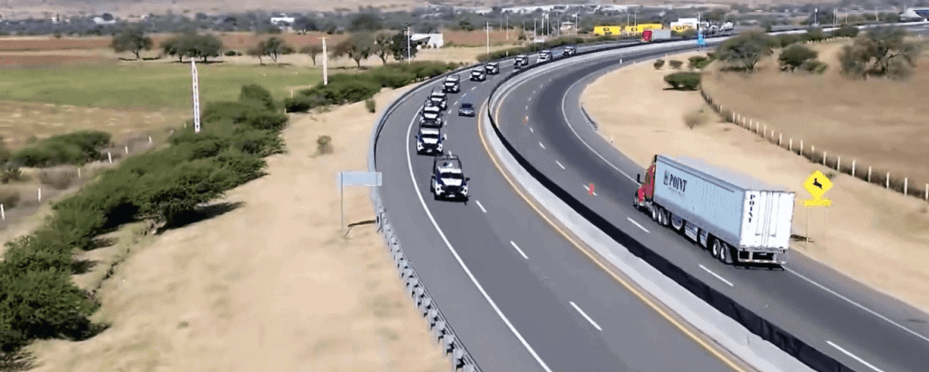Autos de policía en una carretera en movimiento, fila de vehículos, paisaje rural, tránsito, seguridad vial.