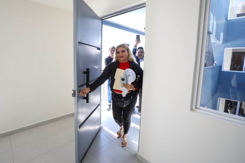 Línea 1: Mujer saliendo de una oficina con teléfono y documentos, en un ambiente de trabajo en México.