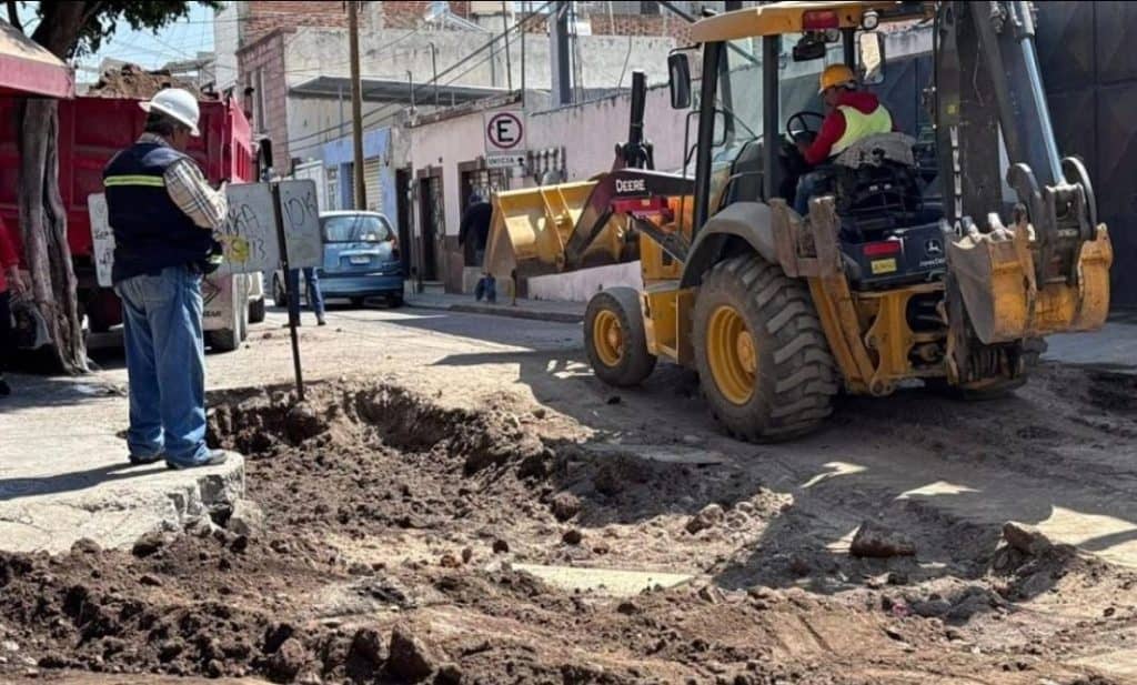 Excavadora trabajando en obra vial en calle urbanizada en México.