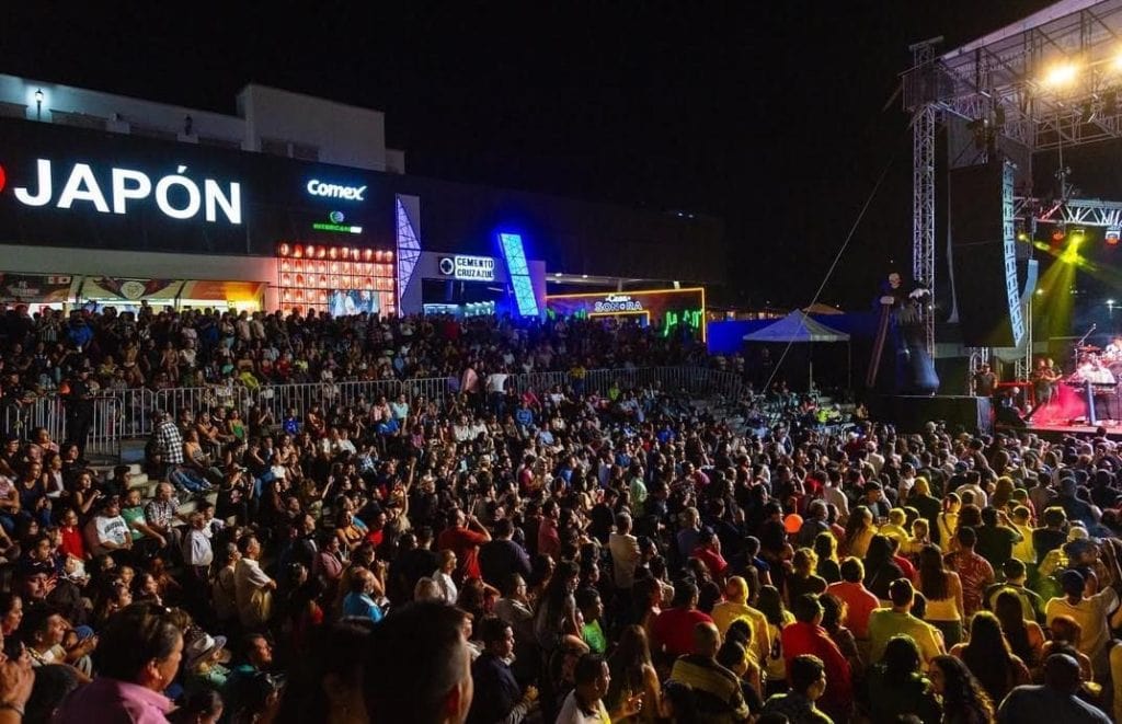Asientos llenos de audiencia en concierto al aire libre en la noche.