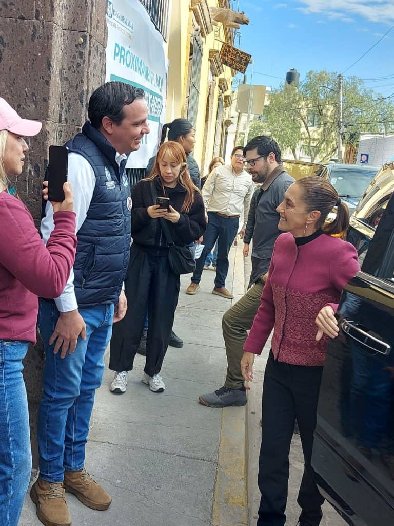 1. Mujeres conversando en la calle con un político, ambiente urbano y día soleado.
