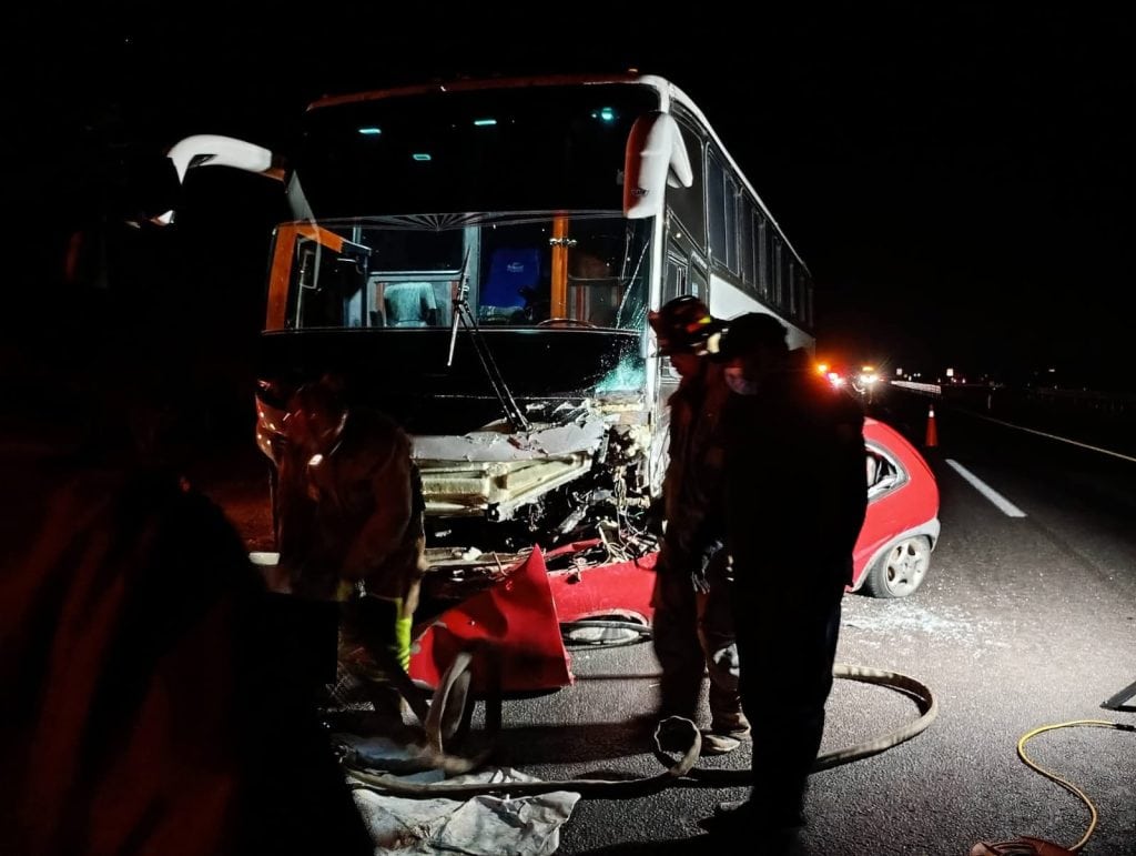 Accidente de autobús en la carretera durante la noche, con bomberos atendiendo la emergencia.