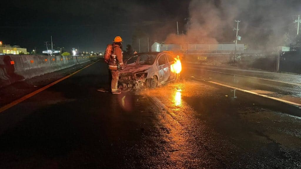 Camioneta en llamas tras accidente en la carretera en la noche.