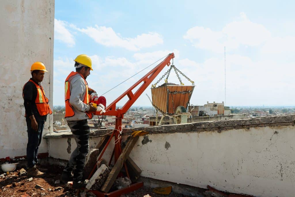 Construcción en proceso con trabajadores usando equipo de seguridad en la azotea de un edificio en Ciudad.