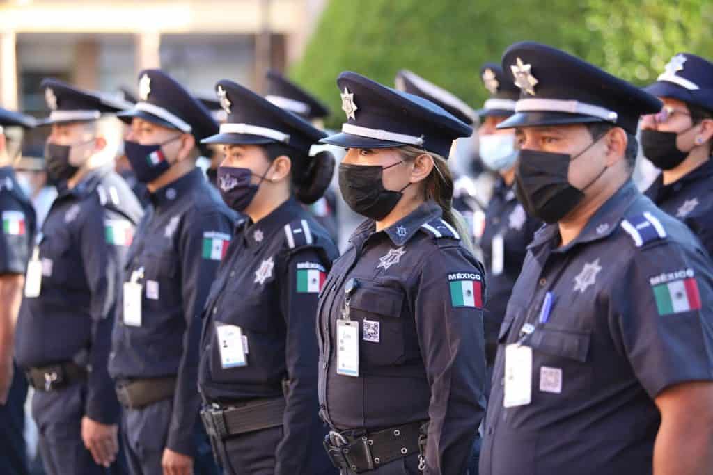 Policías mexicanas en desfile, usando uniformes y mascarillas, en acto oficial de seguridad.