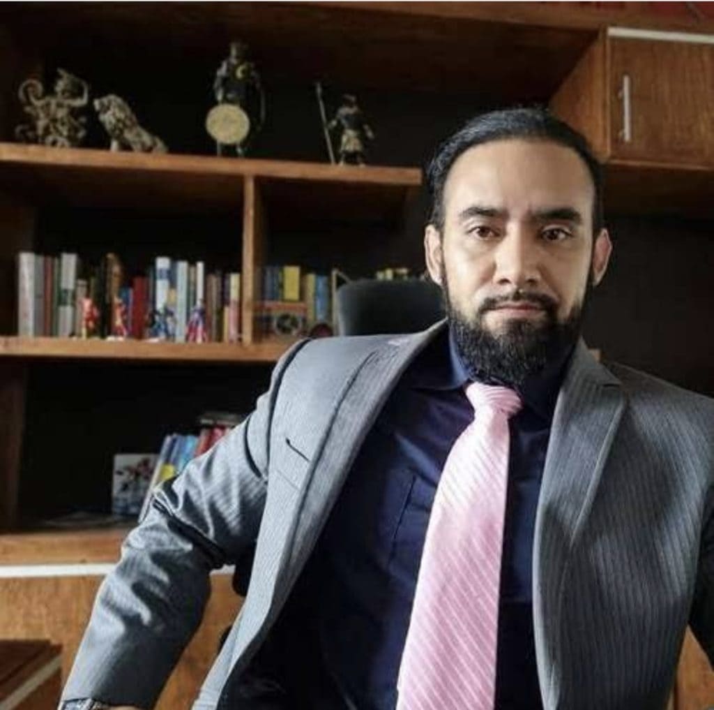 Intelectual hombre de negocios en oficina con estantería de libros y decoraciones culturales.